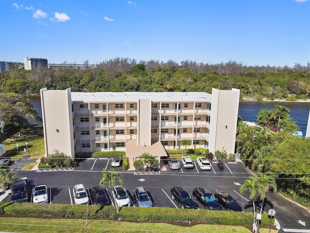 view of building exterior with uncovered parking and a water view