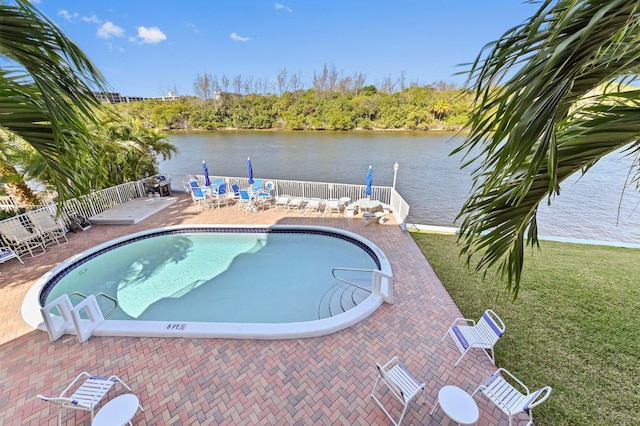 community pool featuring a water view, fence, and a patio area