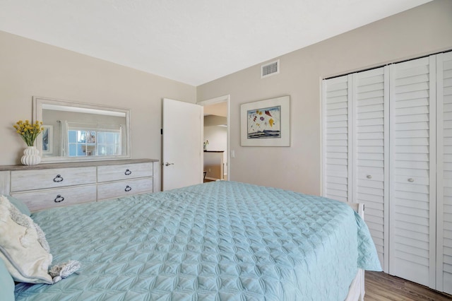 bedroom with visible vents, a closet, and wood finished floors