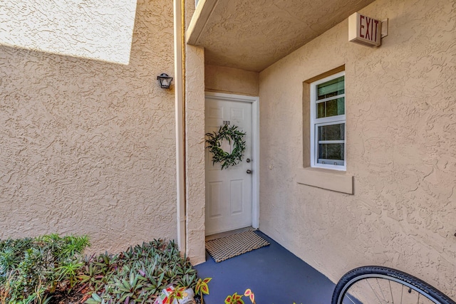 doorway to property featuring stucco siding