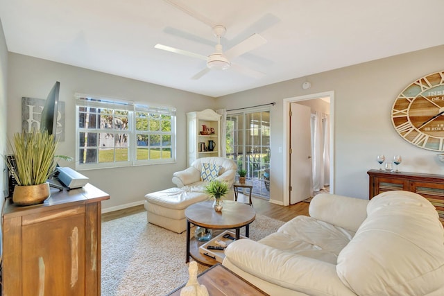 living room with baseboards, wood finished floors, and a ceiling fan