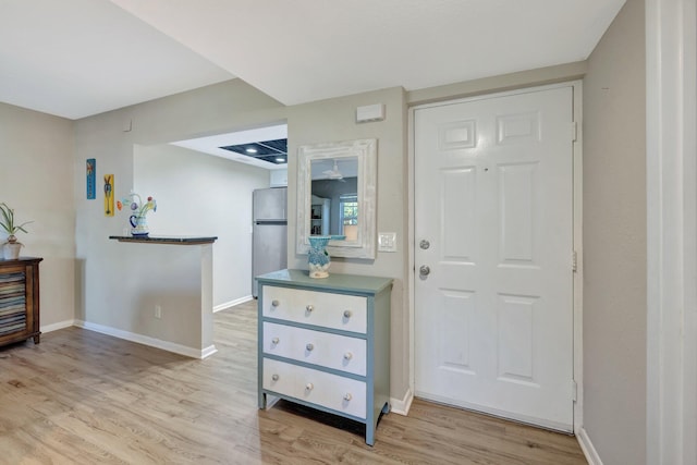 foyer with light wood-style flooring and baseboards