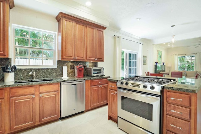 kitchen with brown cabinets, a sink, dark stone countertops, appliances with stainless steel finishes, and decorative backsplash