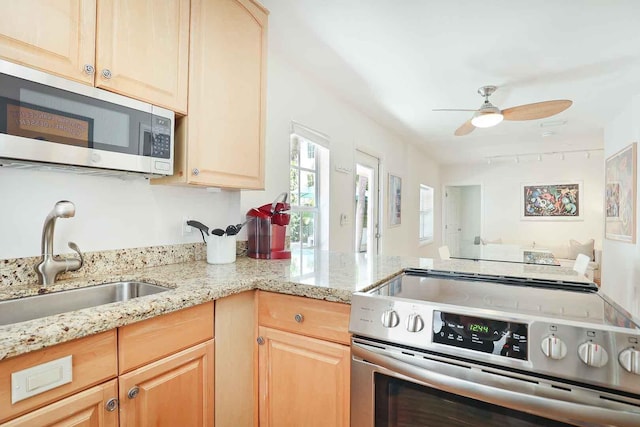 kitchen with light brown cabinetry, a sink, appliances with stainless steel finishes, light stone countertops, and ceiling fan