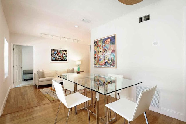 dining area with rail lighting, wood finished floors, visible vents, and baseboards