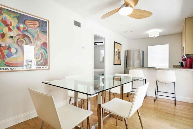 dining room with ceiling fan, light wood-style floors, visible vents, and baseboards