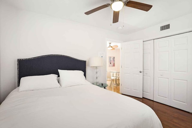 bedroom with wood finished floors, visible vents, a closet, and ceiling fan