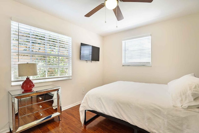 bedroom featuring baseboards, multiple windows, wood finished floors, and a ceiling fan