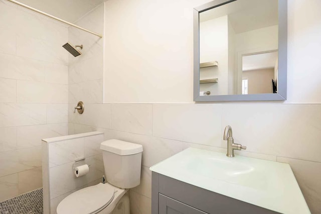 full bathroom with vanity, tile walls, toilet, and a tile shower