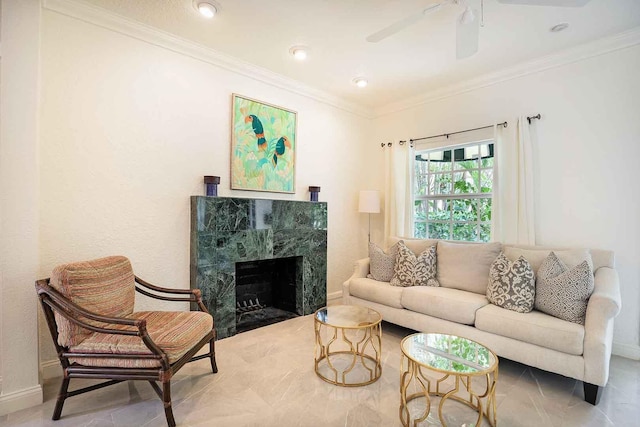 living room featuring ceiling fan, a tile fireplace, baseboards, and ornamental molding