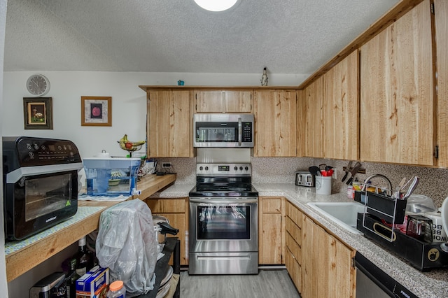 kitchen with light wood finished floors, appliances with stainless steel finishes, light countertops, and decorative backsplash