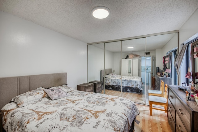 bedroom with a closet, visible vents, light wood-style flooring, and a textured ceiling