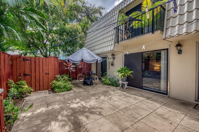 view of patio featuring a gate, fence, and a balcony