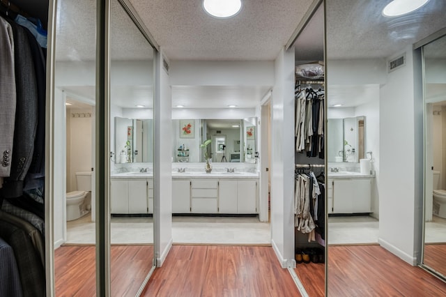 full bath featuring visible vents, vanity, wood finished floors, and toilet