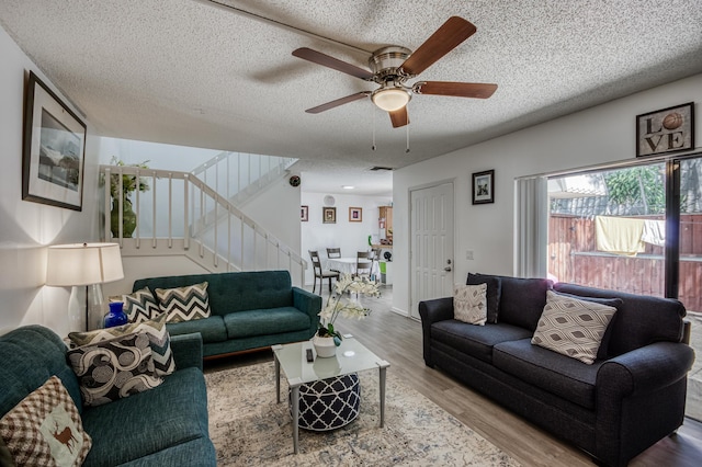 living room featuring visible vents, a ceiling fan, stairway, wood finished floors, and a textured ceiling