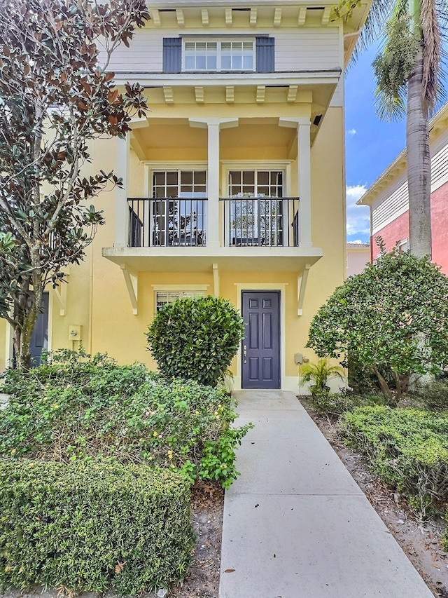 view of exterior entry with a balcony and stucco siding