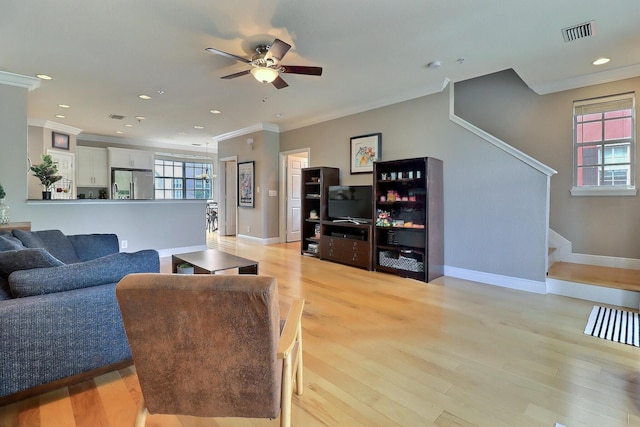 living area with a healthy amount of sunlight, stairway, light wood-style flooring, and visible vents