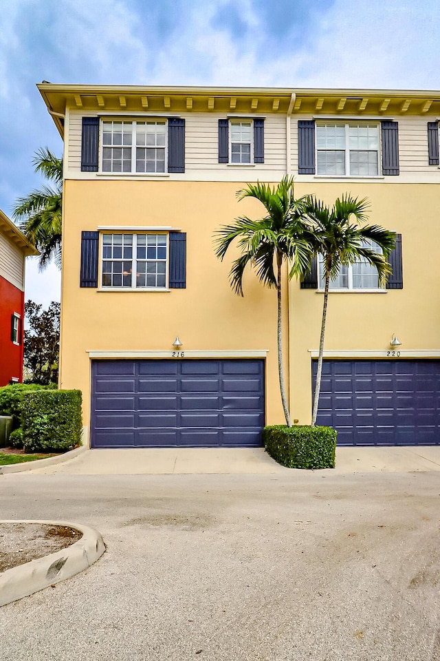 townhome / multi-family property featuring a garage, driveway, and stucco siding