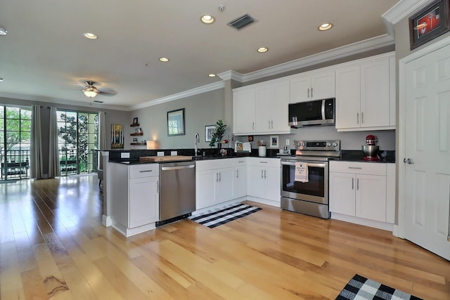 kitchen with a peninsula, appliances with stainless steel finishes, dark countertops, and visible vents