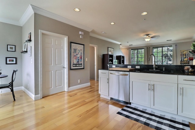 kitchen featuring dishwasher, ornamental molding, a sink, and light wood-style flooring