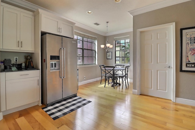 kitchen featuring dark countertops, ornamental molding, high end refrigerator, and light wood-style flooring