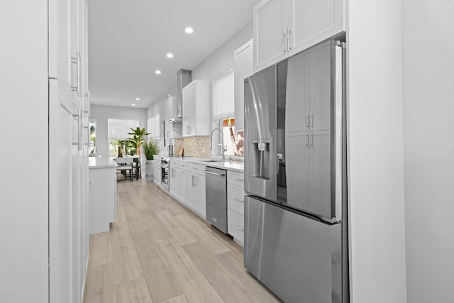 kitchen featuring tasteful backsplash, white cabinetry, recessed lighting, stainless steel appliances, and light countertops