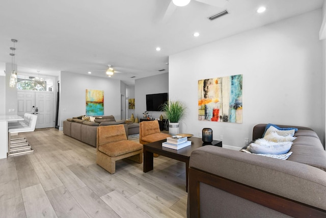 living room with recessed lighting, visible vents, light wood-style flooring, and ceiling fan with notable chandelier