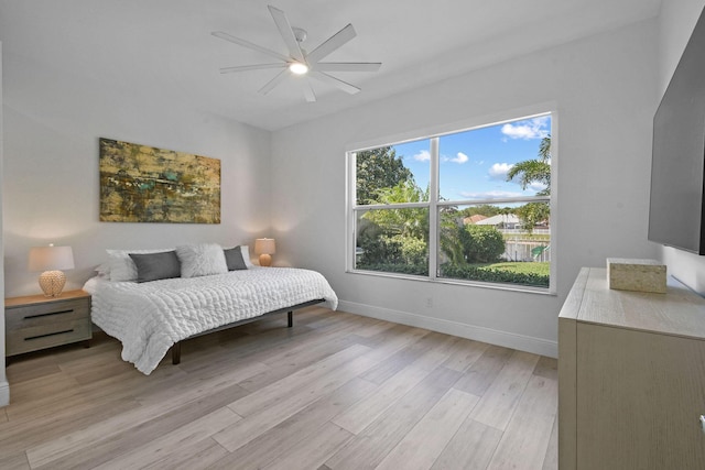 bedroom featuring baseboards, light wood-type flooring, and ceiling fan