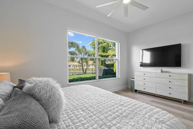 bedroom with light wood-type flooring, baseboards, and a ceiling fan