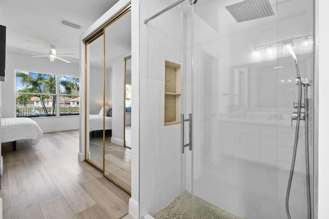 ensuite bathroom featuring a ceiling fan, wood finished floors, visible vents, a shower stall, and ensuite bathroom