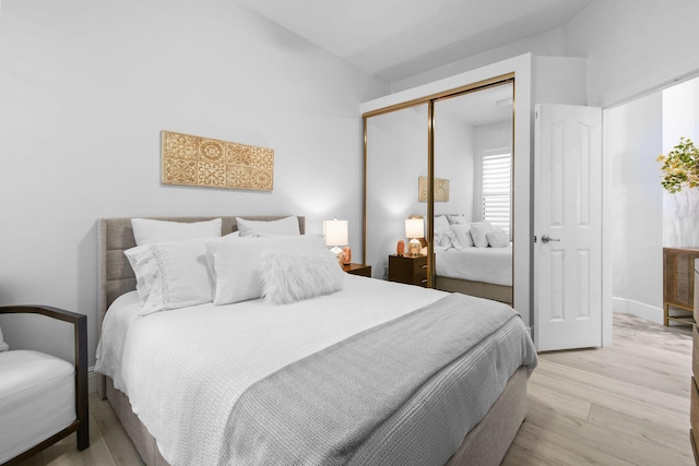 bedroom with a closet, light wood-type flooring, and baseboards