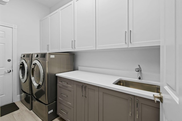 laundry area featuring cabinet space, washer and dryer, and a sink