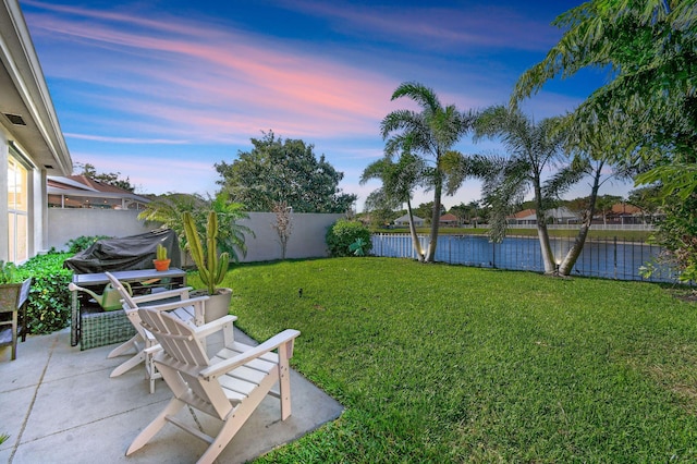 yard at dusk featuring a fenced backyard and a patio