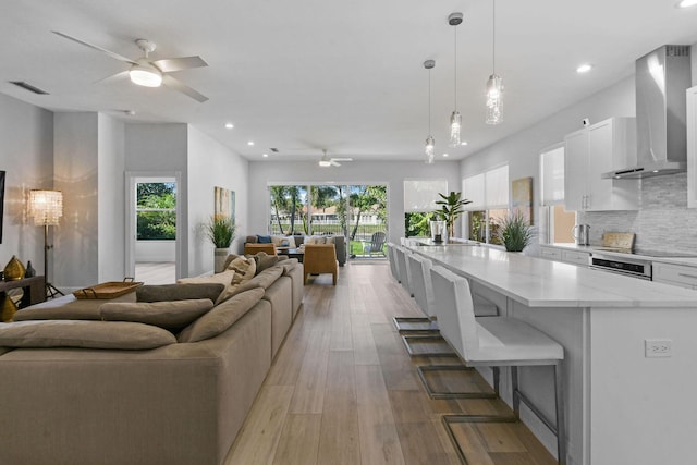 living room with recessed lighting, visible vents, light wood-style flooring, and ceiling fan