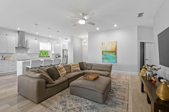 living area featuring baseboards, visible vents, recessed lighting, ceiling fan, and light wood-type flooring