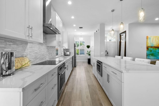 kitchen featuring tasteful backsplash, oven, wall chimney exhaust hood, black electric cooktop, and a sink