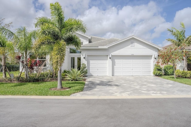 view of front facade featuring decorative driveway, a tiled roof, an attached garage, and stucco siding