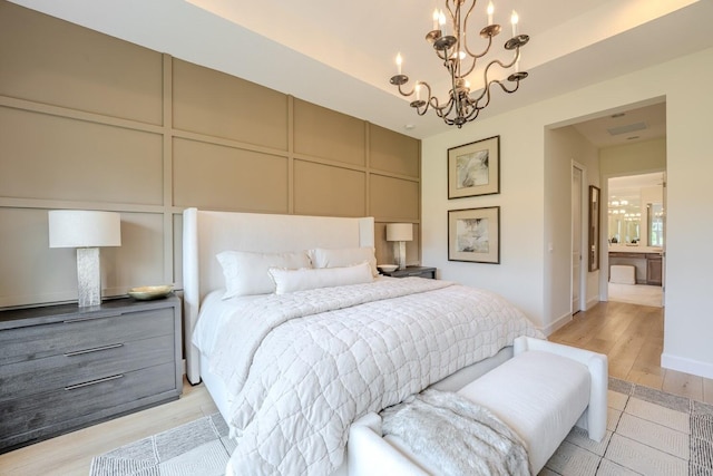 bedroom featuring light wood finished floors, baseboards, a decorative wall, and a notable chandelier