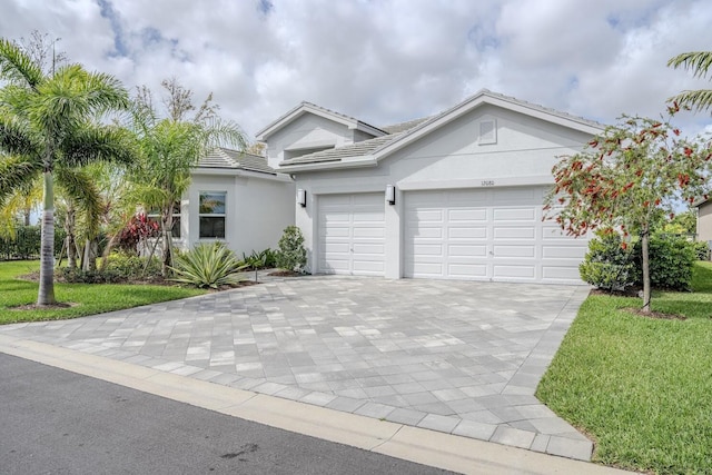 ranch-style home featuring a garage, decorative driveway, a front lawn, and stucco siding