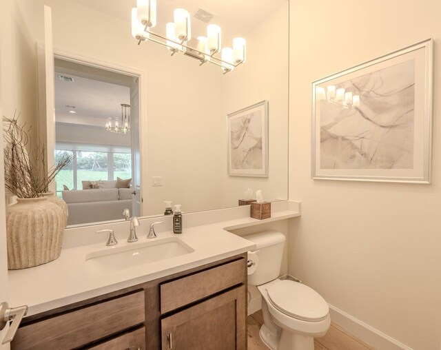 bathroom featuring toilet, visible vents, baseboards, vanity, and an inviting chandelier