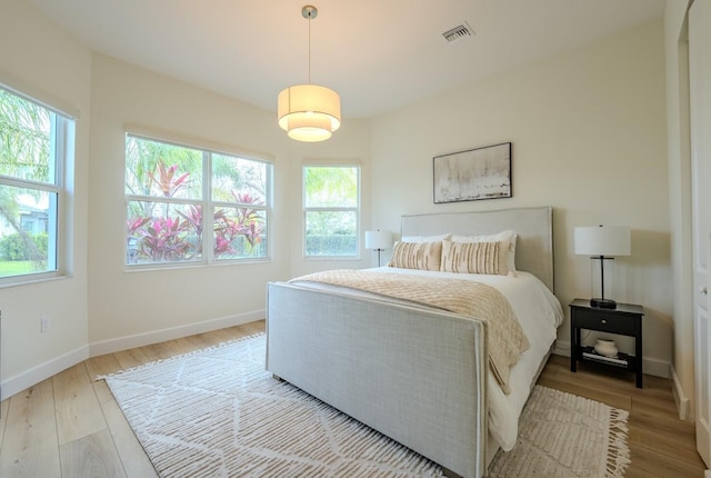 bedroom with visible vents, baseboards, and wood finished floors