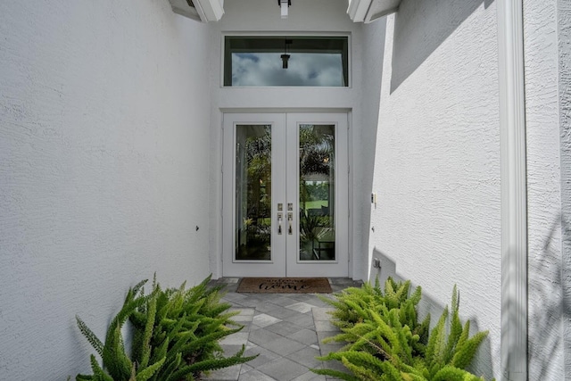 entrance to property featuring stucco siding and french doors