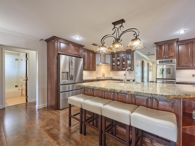 kitchen featuring stainless steel appliances, ornamental molding, a sink, wall chimney range hood, and light stone countertops