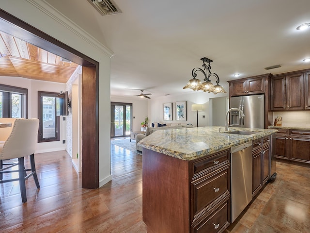 kitchen with open floor plan, stainless steel appliances, visible vents, and light stone countertops