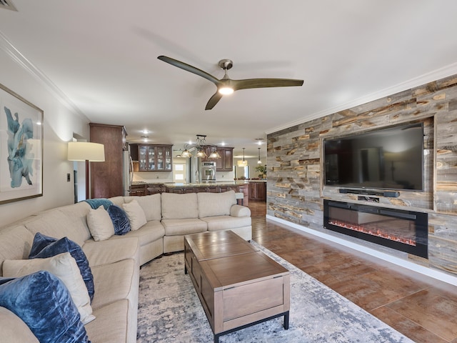 living room featuring ceiling fan, ornamental molding, and a glass covered fireplace