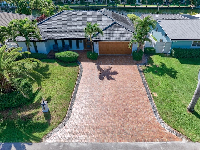 view of front of house featuring a front lawn, decorative driveway, a tile roof, and fence