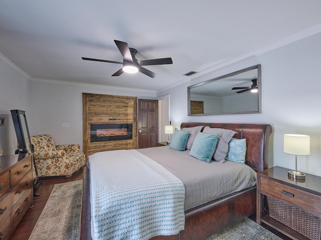 bedroom with ornamental molding, a glass covered fireplace, dark wood finished floors, and visible vents