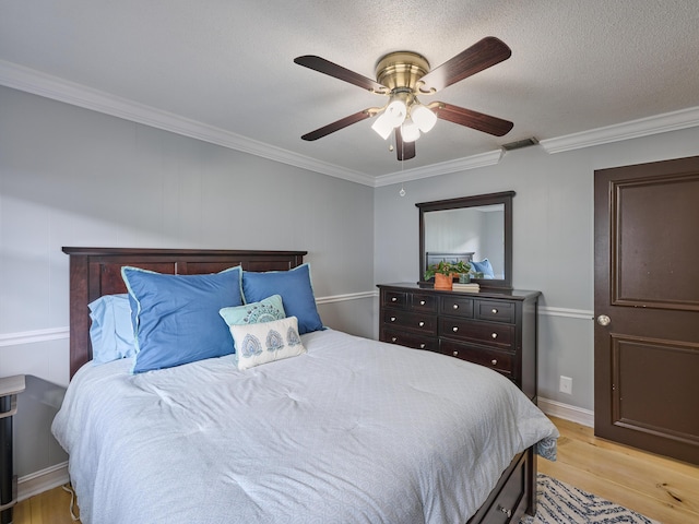 bedroom with light wood finished floors, visible vents, ceiling fan, ornamental molding, and a textured ceiling