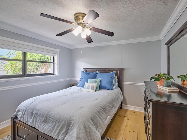 bedroom featuring a textured ceiling, ornamental molding, and light wood-type flooring