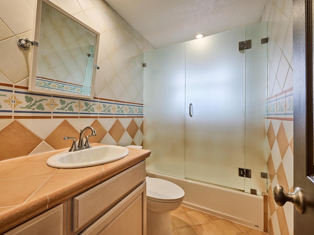 full bathroom featuring toilet, vanity, combined bath / shower with glass door, tile patterned floors, and tasteful backsplash